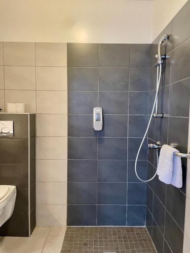 un bagno con doccia e telefono a muro di Hotel L'Escale ad Aigues-Mortes