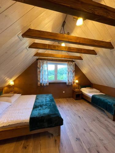 a attic bedroom with two beds and a window at Domki BIERWIONO in Cisna