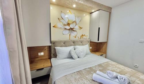 a bedroom with a large bed with a flower on the wall at Apartments St Jakov in Međugorje