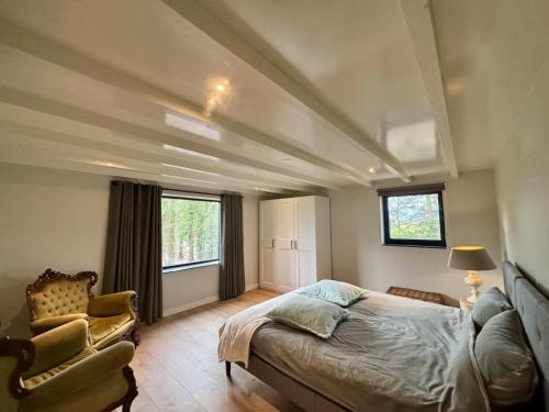 a bedroom with a bed and a chair and windows at Luxe recreatiebungalows midden in bosrijke omgeving Waalre Noord-Brabant in Waalre