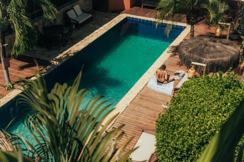 a woman sitting next to a swimming pool at Pipa Panorama Flats&Apartamentos in Pipa