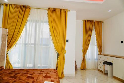 a bedroom with yellow curtains and a bed and a fireplace at Yande Homes in Mama