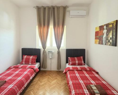 two beds in a room with a window at Apartmani Home in Zaječar
