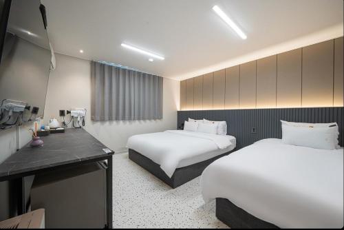 a hotel room with two beds and a desk at EG Stay Hotel in Gwangju