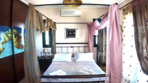 a bedroom with a canopy bed with pink curtains at Villa Arena Theologos in Theologos