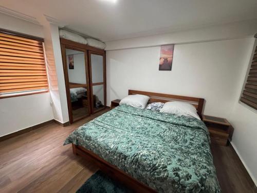 a bedroom with a bed with a green blanket at Green Life Apartment in Sakumona