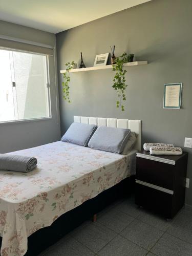 a bedroom with a bed with a table and a window at Casa aconchegante em Aracaju na Aruana in Aracaju