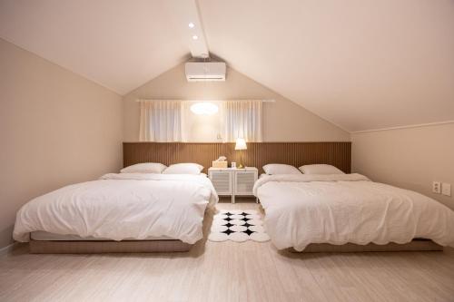 two beds in a attic bedroom with white sheets at GreeneStay Sindang DDP Seoul in Seoul