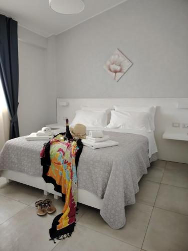 a bedroom with a white bed with a table and shoes at OndaMaris Tropea in Tropea
