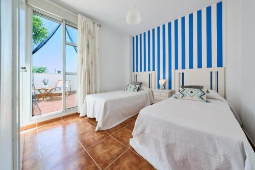 two beds in a room with a view of the ocean at Life Apartments Costa Ballena in Costa Ballena