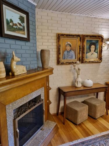 a living room with a fireplace and portraits on the wall at Hotel Vovó Carolina in Gramado