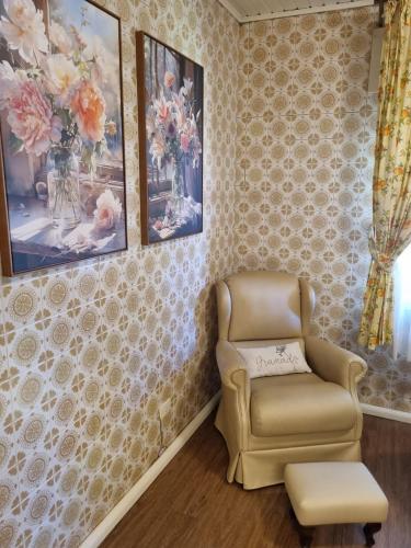 a living room with a chair and pictures on the wall at Hotel Vovó Carolina in Gramado
