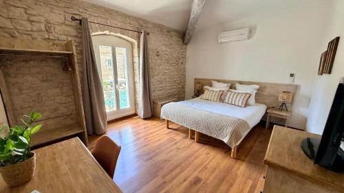 a bedroom with a bed and a table and a window at Hotel Le Galambre in Nîmes
