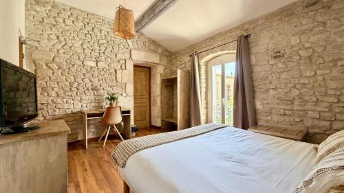 a bedroom with a bed and a stone wall at Hotel Le Galambre in Nîmes