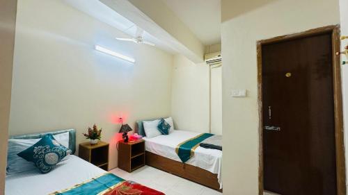 a small bedroom with two beds and a door at Dhanmondi Lake View Hotel in Dhaka