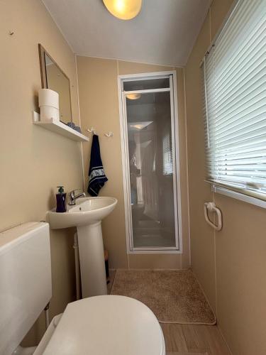 ein Badezimmer mit Waschbecken, Toilette und Fenster in der Unterkunft Chalet Beau in Westerland