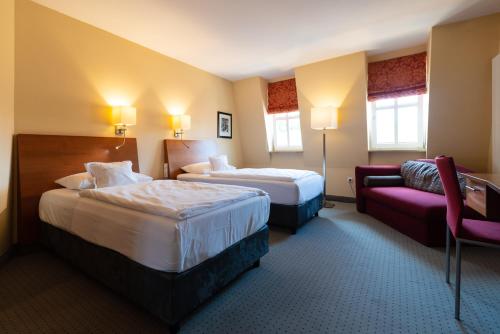 a hotel room with two beds and a couch at Hotel am Torturm in Volkach