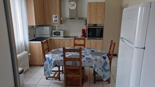 a kitchen with a table with chairs and a refrigerator at Maison, jardin, barbecue et vélo classé 3 étoiles in Dives-sur-Mer