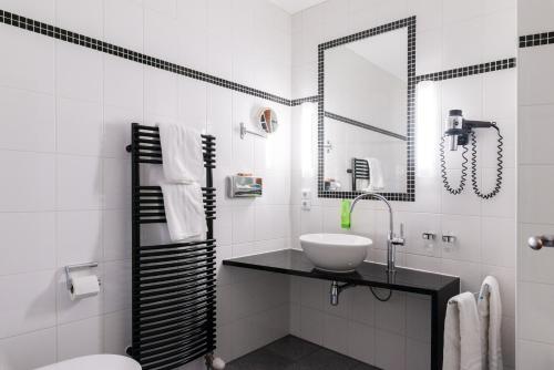 a white bathroom with a sink and a mirror at Hotel am Torturm in Volkach