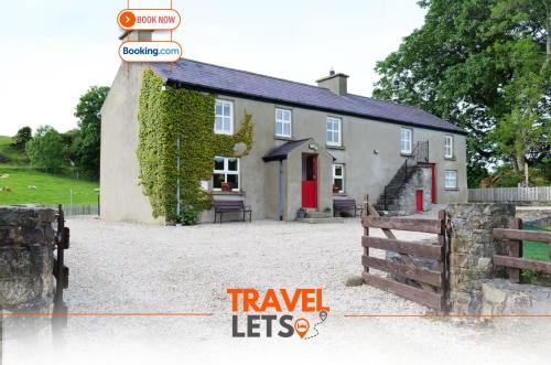 a white house with a red door and a fence at 5BR Farmhouse By Travel Lets Holiday Rentals Donegal in Carrigart
