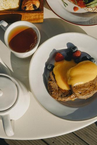 a plate with a pancake with fruit and a cup of tea at Aethos Hotel Ericeira in Ericeira