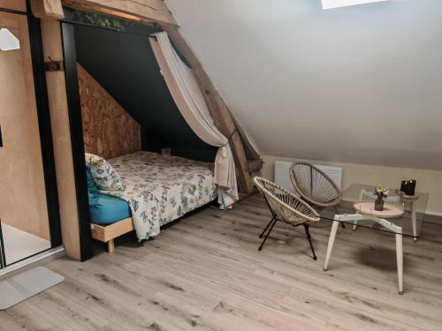 a bedroom with a bed and a table and a chair at Le refuge du chat endormi in Goderville