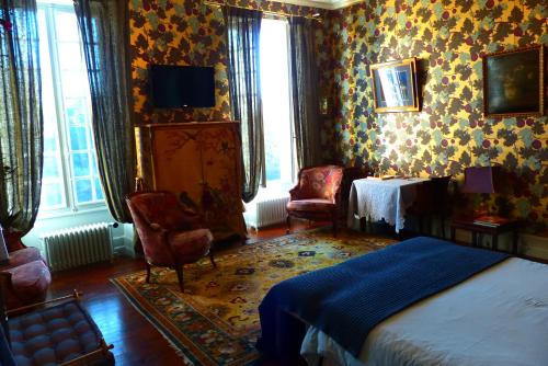 a bedroom with a bed and chairs in a room at La Rebière d'Or, B&B et Gîte in Mouleydier