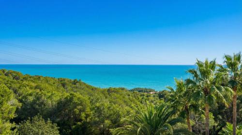a view of the ocean from a hill with palm trees at Villa Kala in Sant Pere de Ribes