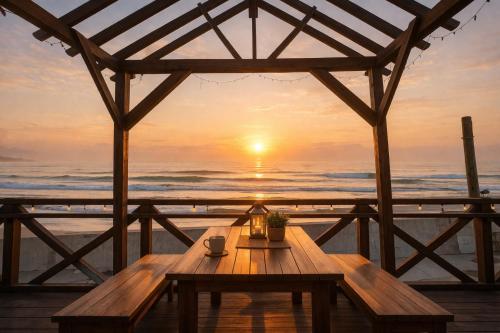 a wooden table on the beach at sunset at Aloha Beach Deck , Oceanfront, Stunning Sunrises, BBQ, Karaoke in Hokota