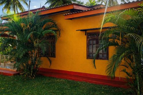 a yellow house with palm trees in front of it at Aqua Dream Adventures Resort in Trincomalee