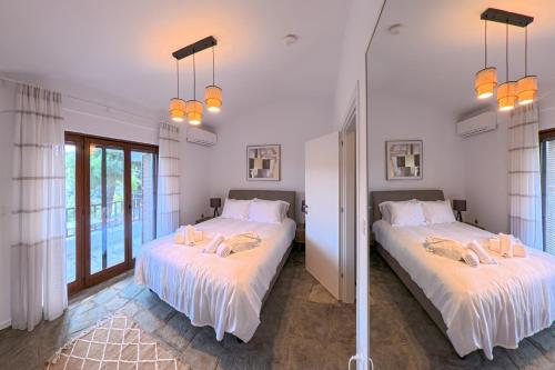 two beds in a room with white walls and windows at Elani Blue Coast Maisonette in Elani