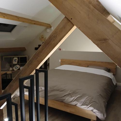 a bed in a loft bedroom with wooden beams at Celessentielle à 10 min de Pairi Daiza , gîte romantique in Jurbise
