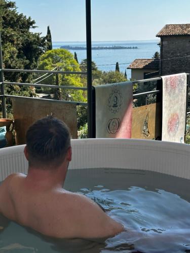 a man in a bath tub with a view of the ocean at Seeblick VILLA LAGUNA BLUE - Private Spa - Whirlpool & Sauna in Gardone Riviera