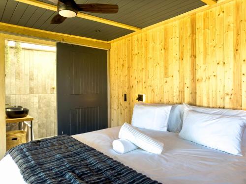 a bed with white pillows in a room with wooden walls at Bietjiedam's The Barn in Caledon