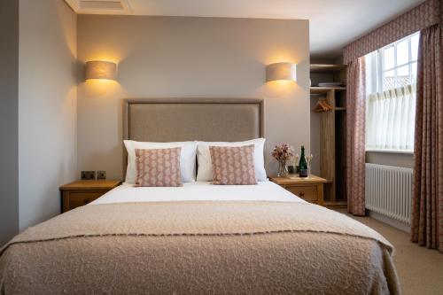 a bedroom with a large bed with pillows and a window at The Bull Inn in Woodbridge
