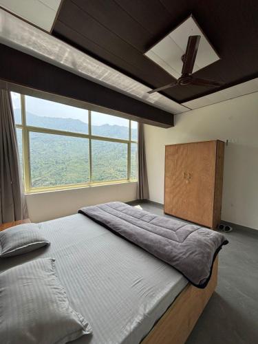 a bedroom with a large bed with a large window at The Jade Inn in Gopeshwar