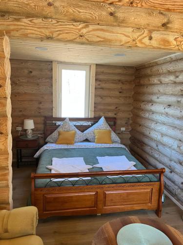 a bedroom with a bed in a log cabin at Miško sodyba in Gedvainiai