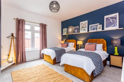 a bedroom with two beds and a blue wall at Boho Chic - Stylish Home in City Centre, Sleeps 4 in Darlington
