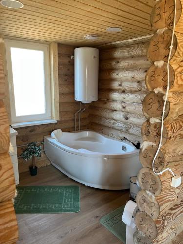 a bathroom with a tub in a wooden wall at Miško sodyba in Gedvainiai