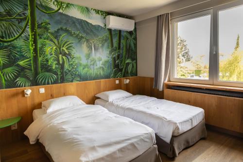 two beds in a room with a mural on the wall at Thermae Grimbergen Hotel in Grimbergen