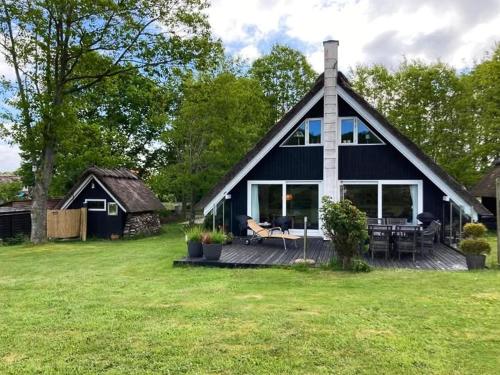 a black and white house with a deck in the yard at Charming House With A View Of The Sea in Båring