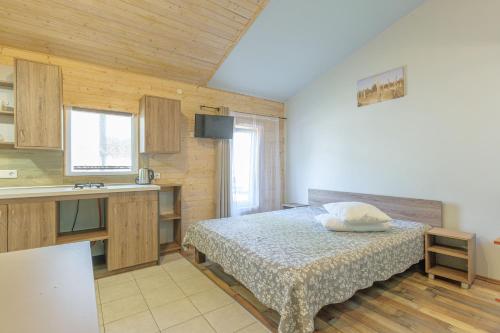 a small bedroom with a bed and a kitchen at 11 kopų in Šventoji