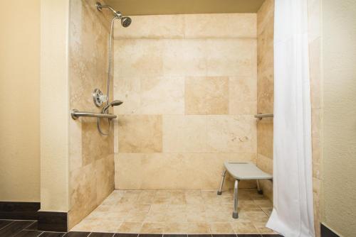 a shower with a bench in a bathroom at Days Inn by Wyndham Joplin in Joplin