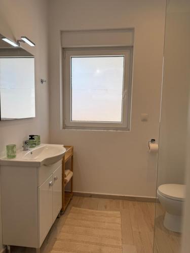 a bathroom with a sink and a toilet and a window at Maison Soleil II in Kastro Kyllini