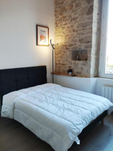a bed in a bedroom with a brick wall at studio moderne les pieds dans l'eau in Larmor-Baden