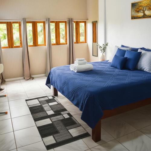 a blue bed in a room with windows at Blue Sky Apartment in Soufrière