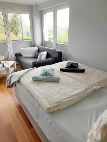 a large white bed in a room with a couch at Marbijes Appartementhaus in Cuxhaven