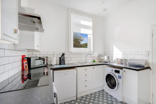a white kitchen with a washing machine and a window at Spacious 3-Bed Home in South Shields, Sleeps 8 in South Shields