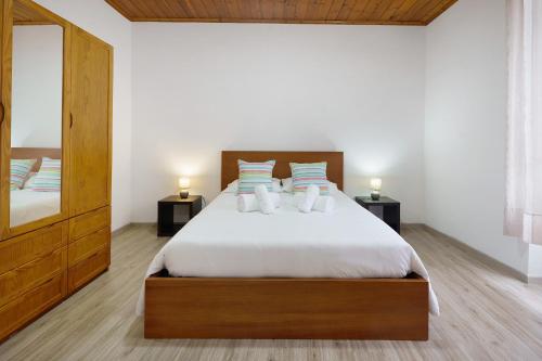 a bedroom with a bed with two night stands and a mirror at Casa Flor de Laranjeira in Faial da Terra