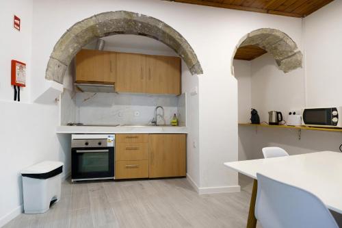 a kitchen with an archway over a sink and a stove at Casa Flor de Laranjeira in Faial da Terra